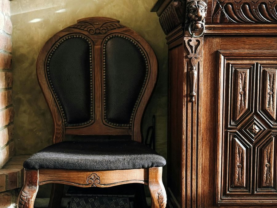 Carved wood chair beside an ornate wood cabinet